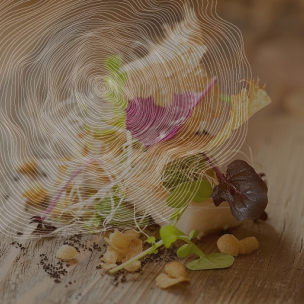 Une assiette en bois contient une quenelle blanche, des pousses, des chips dorées et des feuilles rouges. Le tout est disposé sur une table en bois.