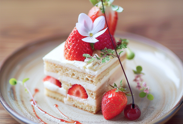 Mains de chef en train de préparer des mochis, saupoudrant de la poudre de matcha sur des boules de riz gluant colorées, disposées méthodiquement sur une table en bois recouverte de farine.