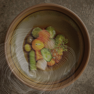 Un bol en céramique contient divers légumes, notamment des tomates, des concombres, des oignons et des herbes. Le bol repose sur une surface texturée. Des lignes blanches ondulées sont superposées à l'image.