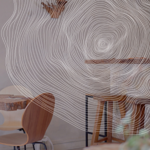 Intérieur minimaliste d'un restaurant avec une table en bois brut, chaises et tabourets en bois clair. Le décor est complété par des murs texturés et un luminaire suspendu qui offre une lumière chaleureuse.