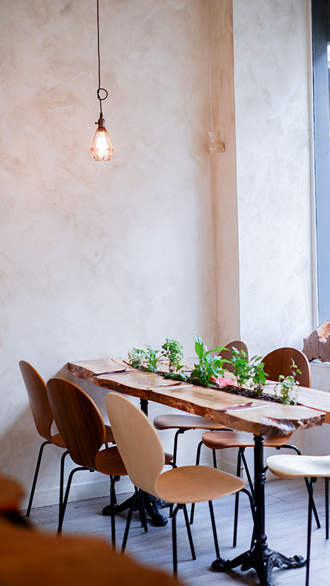 Intérieur chaleureux du restaurant Lacigne avec tables en bois et décoration végétale épurée.