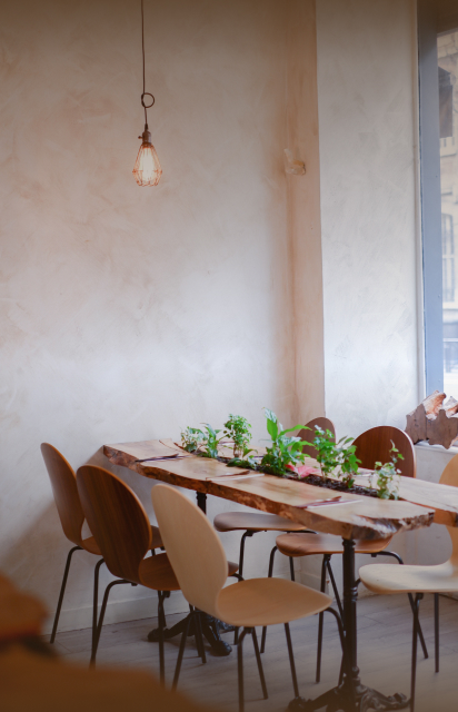 Intérieur chaleureux du restaurant Lacigne avec tables en bois et décoration végétale épurée.